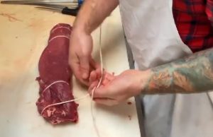 Skillman head butcher breaking down whole beef tenderloin